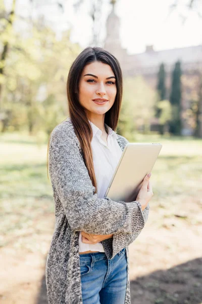 Jovem mulher andando no parque com laptop nas mãos — Fotografia de Stock