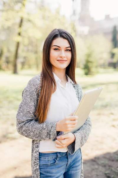 Mulher muito jovem andando com laptop sob a mão no parque — Fotografia de Stock