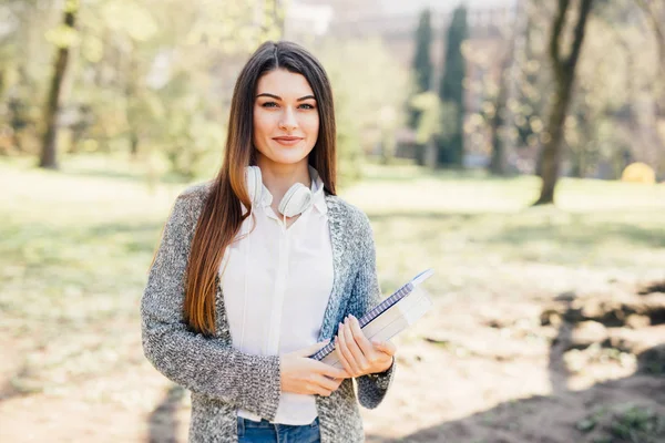 Hezká mladá žena s notebookem pod ruku v parku — Stock fotografie