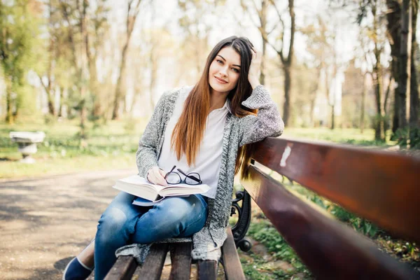 Красивий студент університету читає в парку на лавці — стокове фото