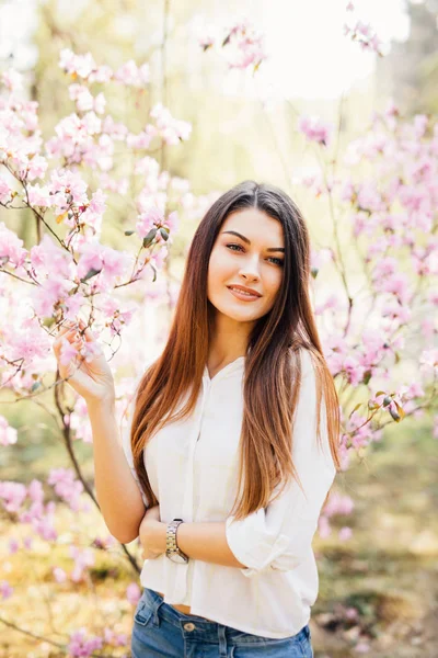 Egy fiatal gyönyörű nő virág, magnolia fa közelében szabadtéri portréja. — Stock Fotó