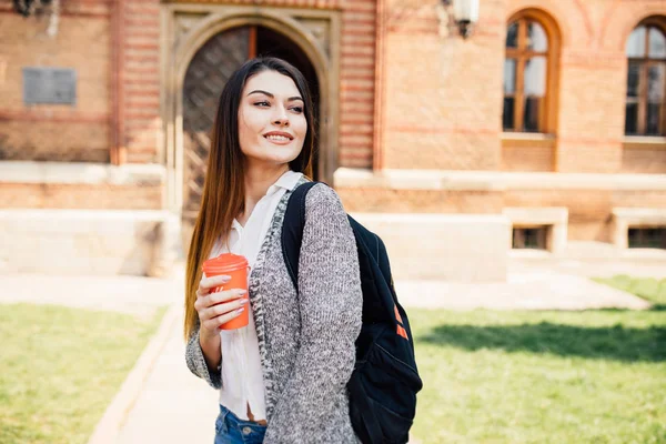 Estudiante universitario estadounidense sonriendo con café y bolsa de libros en el campus — Foto de Stock
