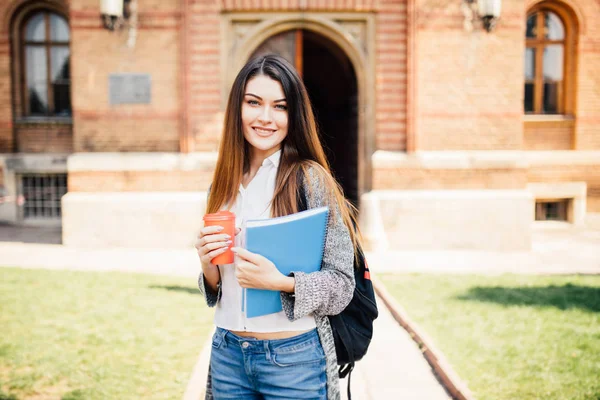 Estudante universitário americano sorrindo com café e saco de livro no campus — Fotografia de Stock