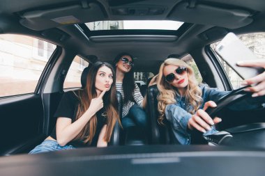 Selfie yapma ve arabaya birlikte otururken gülümseyen üç güzel genç neşeli kadın görünümünü