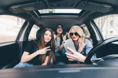 Selfie yapma ve arabaya birlikte otururken gülümseyen üç güzel genç neşeli kadın görünümünü