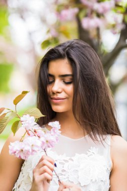 Neşeli pozitif Kafkas kadın çiçekli sakura ağacı ile poz.