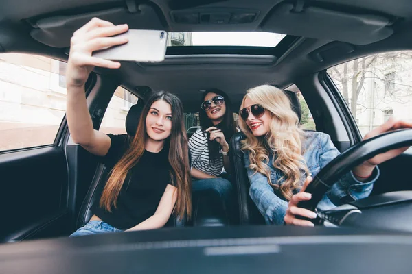 Όμορφα κομψό κορίτσια κάνουν selfie, βλέπουν φωτογραφική μηχανή που έχει τη διασκέδαση ενώ κάθεστε στο αυτοκίνητο — Φωτογραφία Αρχείου
