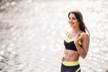 Daha önce eğitim göl arka plan karşı parkta duran genç fitness kadın