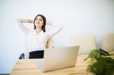 İş kadını ellerini başının arkasına koyup bir ofis sandalyesinde oturuyor.