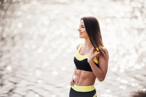 Mujer fitness joven de pie en el parque antes de entrenar contra el fondo del lago — Foto de Stock