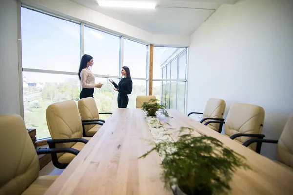 Två affärskvinnorna talar på ett kontor nära stora panoramafönster — Stockfoto