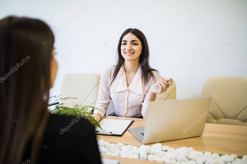 Two businesswomen colleagues talking together in office