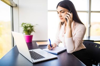 Mobil telefonda konuşurken ve ofis onun çalışma evinde oturan ve laptop arıyorum gülümseyen çekici genç kadın