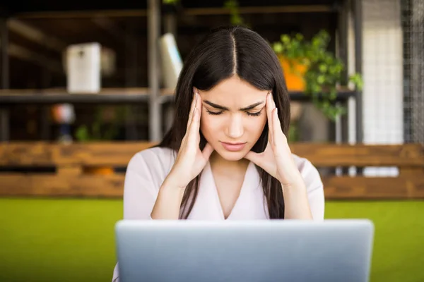 Ung affärskvinna lider av huvudvärk framför laptop på kontoret — Stockfoto