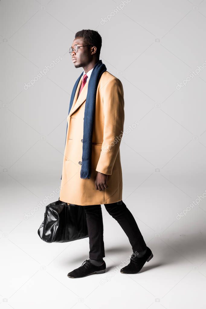 Black businessman with bag in coat on white background