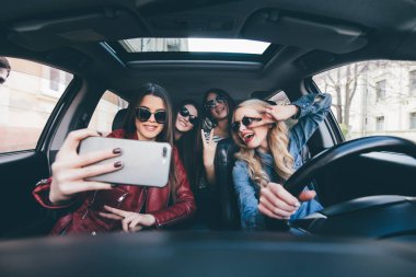 Eğleniyor araba ve alma selfies kamera ile yolculuğa kız grubu