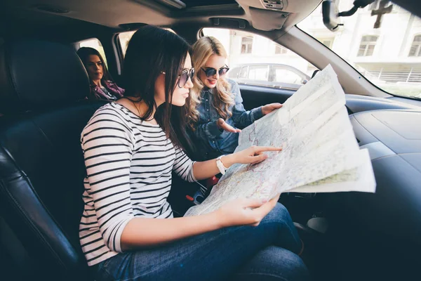 Γυναίκες στις διακοπές, κοιτάζοντας το χάρτη για οδηγίες κατά την οδήγηση στο αυτοκίνητο — Φωτογραφία Αρχείου