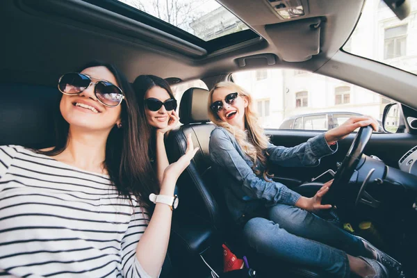 Vier mooie jonge vrolijke vrouwen die kijken naar elkaar met glimlach zittend in de auto — Stockfoto