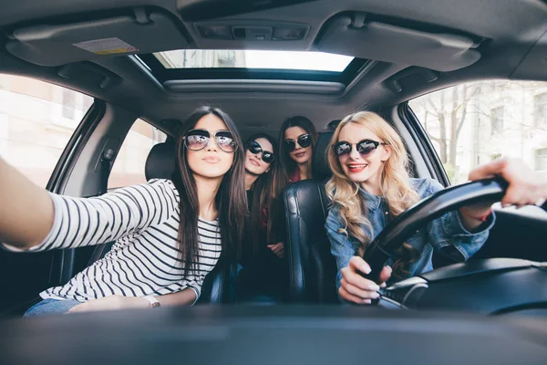 Група дівчат розважаються в машині і приймають селфі з камерою в дорожній поїздці — стокове фото