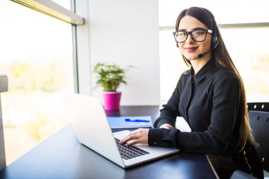 Ofiste kulaklıklarla gülümseyen kadın yardım hattı operatörü