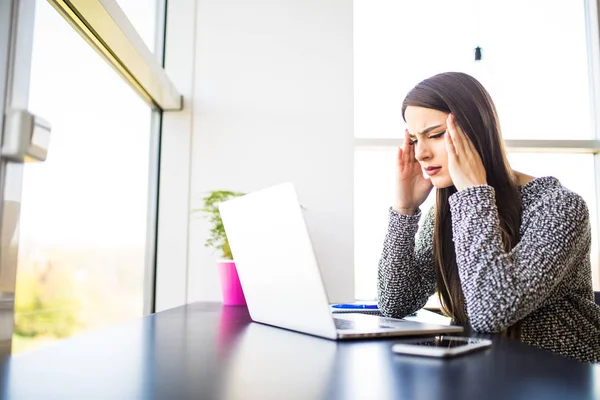 Trött överarbetade frilansare arbetar med en laptop i ett kontor eller i hemmet — Stockfoto