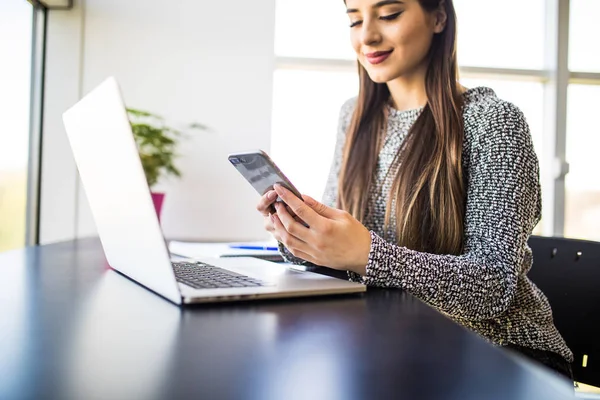 Hermosa chica freelancer éxito utilizando ordenador portátil y escribir mensaje de texto en el teléfono — Foto de Stock