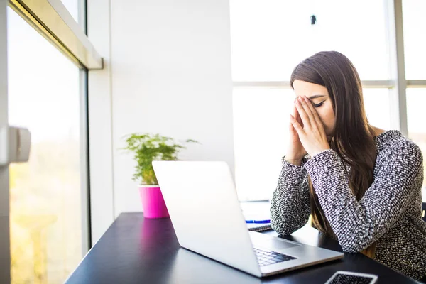 Vackra trött affärskvinna håller massera sin näsa bro medan arbetande i kontor — Stockfoto