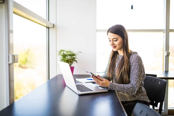 Porträtt av vackra upptagen kvinna med hemma mobiltelefon och bärbar dator samtidigt i office — Stockfoto