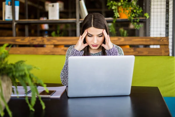 Ung frustrerad kvinna som arbetar på kontoret skrivbord framför laptop lider av kronisk daglig huvudvärk — Stockfoto