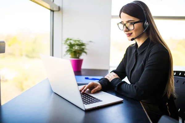 Sonriente operadora de línea de ayuda femenina con auriculares en la oficina — Foto de Stock