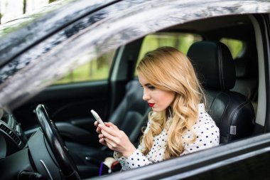 Kullanarak ve yolda bir araba akıllı telefon bakarak kadın