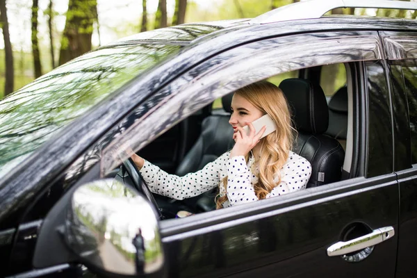 Joven hermosa mujer llamando al teléfono mientras conduce un coche en la calle — Foto de Stock
