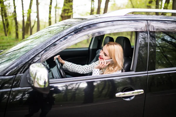 Hermosa mujer está hablando en el teléfono móvil y sonriendo mientras está sentado en el coche — Foto de Stock