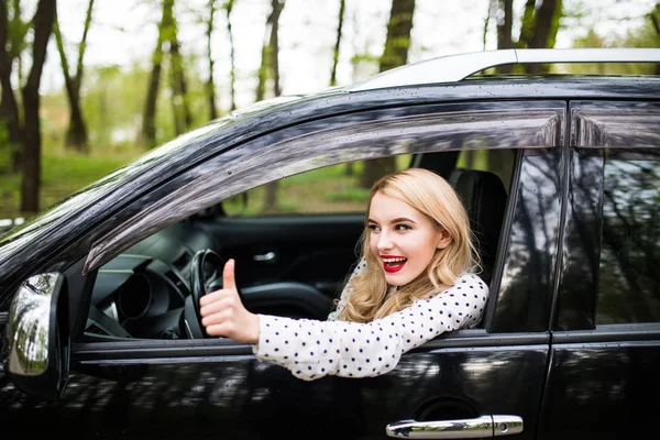 Retrato de cerca de una hermosa joven con pulgares en su coche nuevo — Foto de Stock