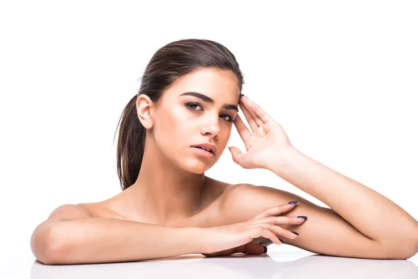 Young woman resting her head on a white desk over white background. Perfect skin, cosmetology. Royalty Free Stock Images