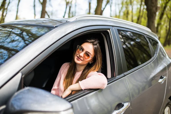 Souriant belle femme brune conduisant une voiture dans la rue — Photo