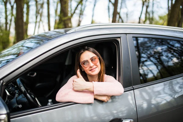 Mulher sentada no carro e mostrando os polegares na rua — Fotografia de Stock