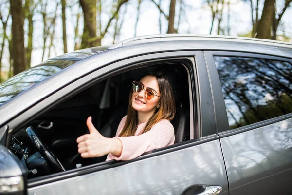 Mulher sentada no carro e mostrando os polegares na rua — Fotografia de Stock