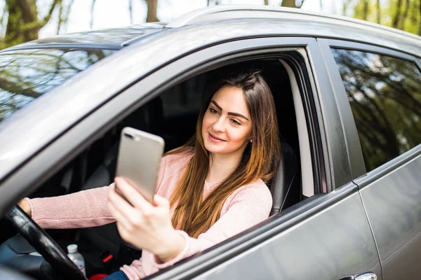 Mão mulher segurando smartphone na janela seu carro — Fotografia de Stock
