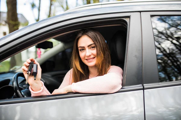 Молодая женщина возле машины с ключами в руке при покупке автомобиля — стоковое фото