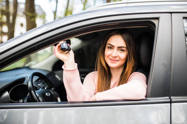 Mulher feliz motorista mostrando chaves do carro e inclinando-se na porta do carro na estrada de rua — Fotografia de Stock