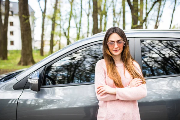 Jeune femme debout à côté de sa nouvelle voiture dans la rue de la ville — Photo