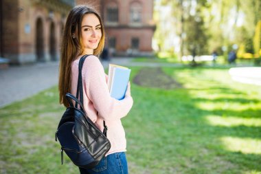 Yazdırma alanı ile kampüste kahve ve kitap çanta ile gülümseyen Üniversitesi Öğrenci