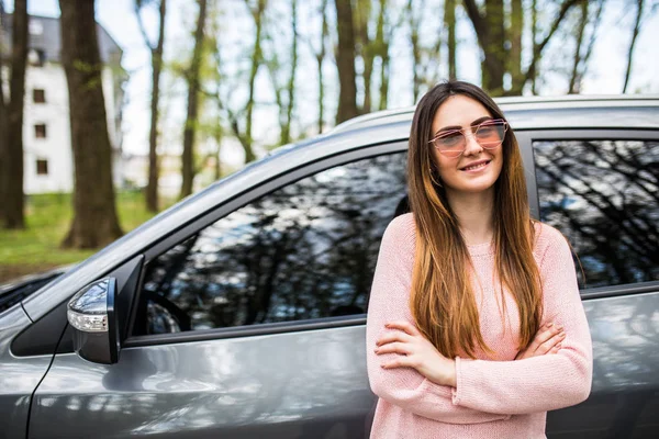 Joven mujer feliz de pie junto a su coche con las manos cruzadas — Foto de Stock