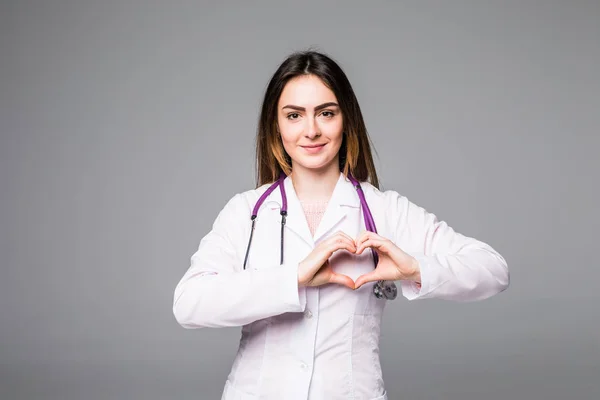 Médico poniendo sus manos en forma de corazón aislado sobre fondo gris — Foto de Stock