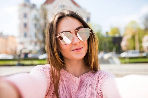 Ung kvinna tar selfie från händerna med mobiltelefon i soliga staden gatan. — Stockfoto