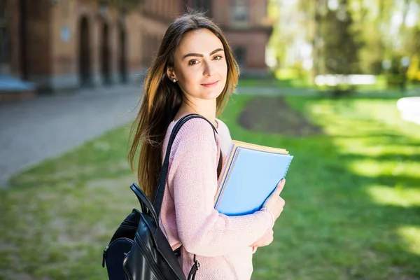 Universidade estudante menina olhando feliz sorrindo com livro ou notebook no parque do campus . — Fotografia de Stock