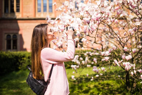 Felice viaggiatore donna scattare foto con la macchina fotografica con albero di ciliegio in vacanza mentre la primavera — Foto Stock