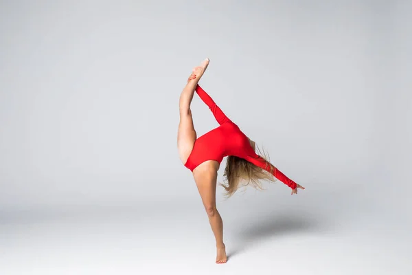 Mladá štíhlá žena dělá akrobatické kaskadérské gymnastické a taneční ecercises na bílém — Stock fotografie
