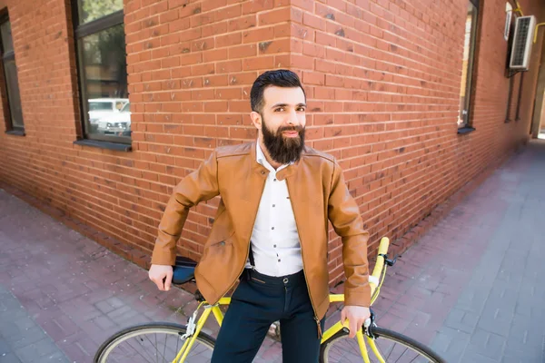 Sakallı bir tuğla arka plan bisiklet üzerinde oturan bir genç şık adam — Stok fotoğraf